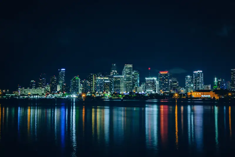 A city skyline lit up at night, reflected in the river. Photograph by Stefano Paolucci