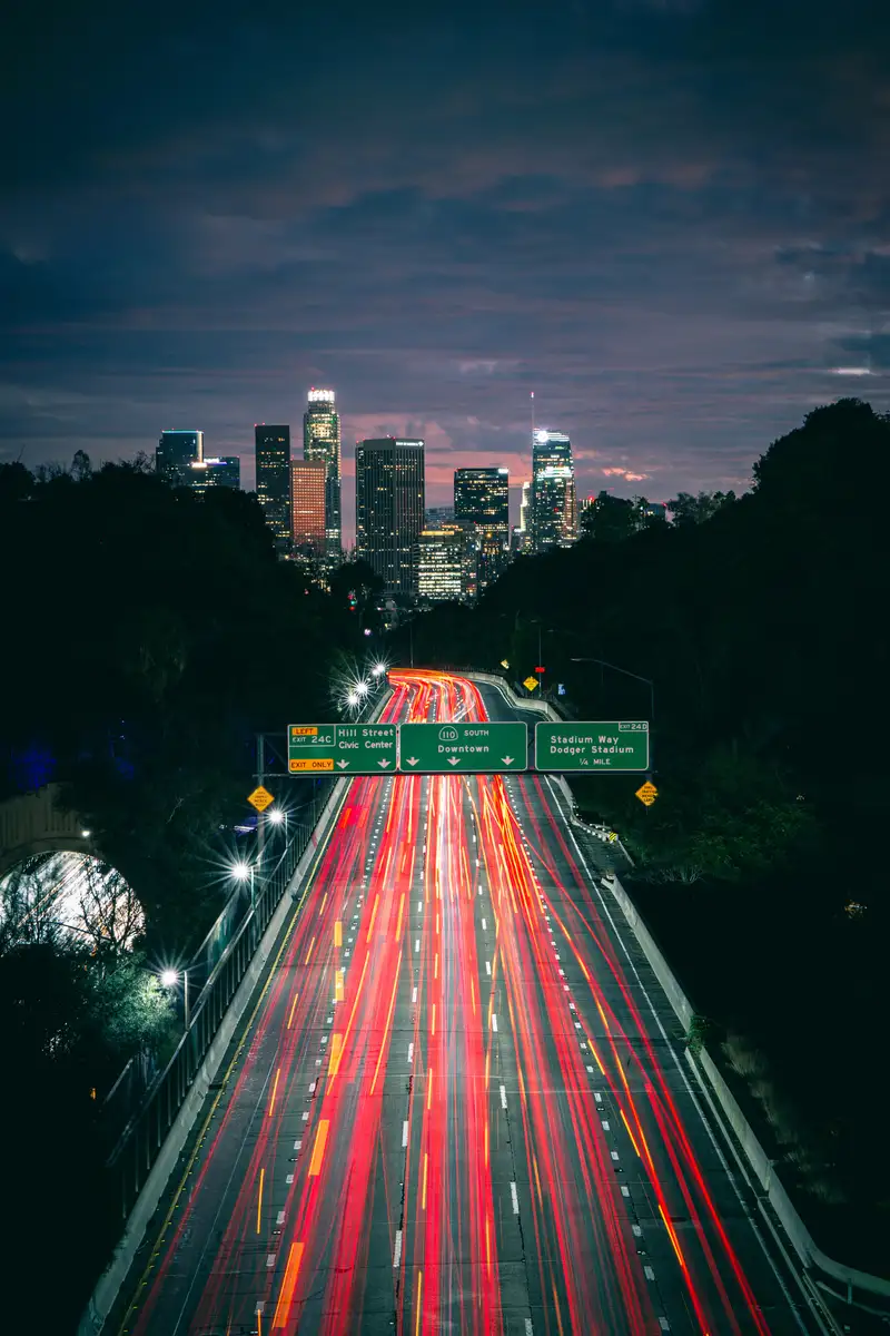 Red and white car light trails on a freeway into downtown at night. Photograph by Stefano Paolucci