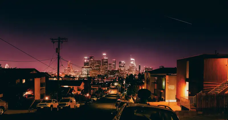 A city at night under a violet sky, between houses and power poles. Photograph by Stefano Paolucci